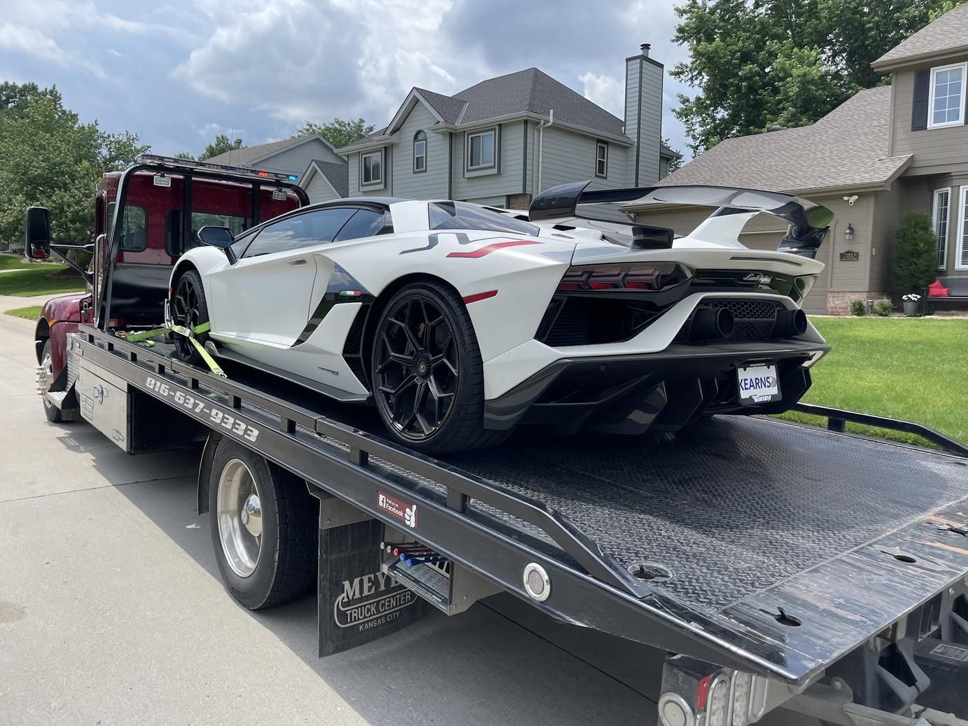White Lamborghini strapped down on the Parsons flatbed on a residential street